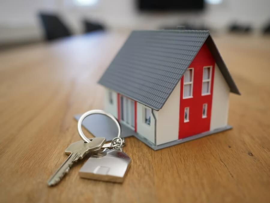 Image d'une maison en format réduit à côté d'une clés pour évoquer la propriété. Cette image évoque l'assurance immobilière proposée par SAGERI